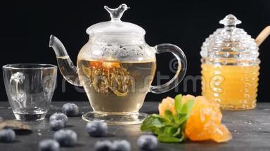 玻璃茶中盛开的绿色中国花茶。 茶道。 蓝莓，玻璃罐加蜂蜜。 饮用开水